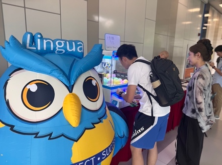 Students taking part in the booth activities beside the Language Centre mascot.