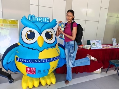 A student posing beside the Language Centre mascot.