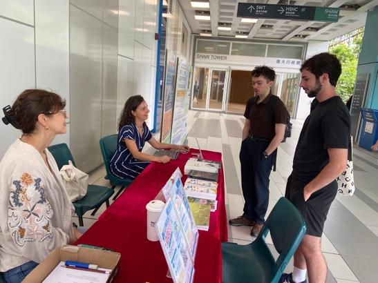Language Centre teachers speaking with students at an information table.