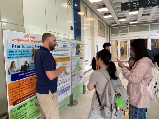 A teacher providing language-support information to students at the booth.